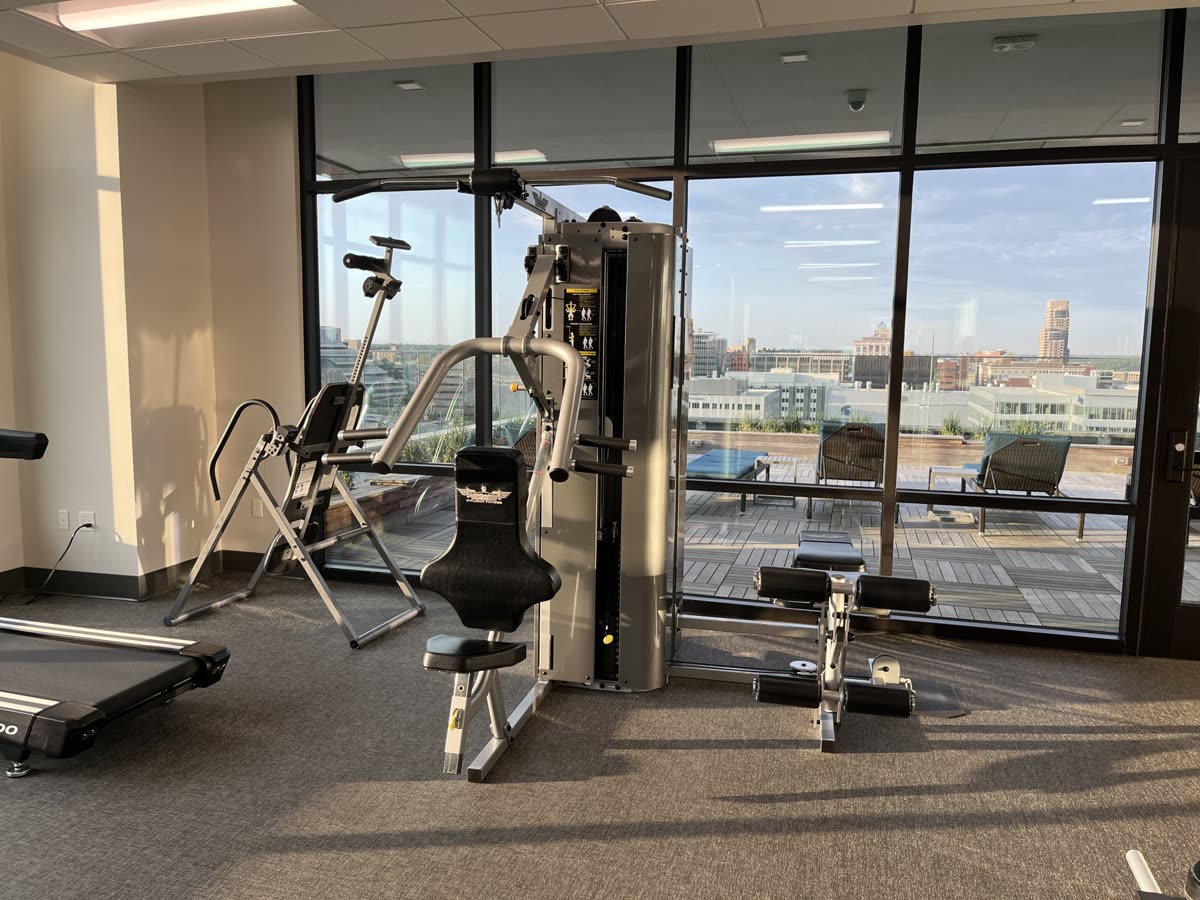 Bench press machine in a small gym with glass walls on the roof of a building. Grand Rapids Michigan visible outside. — 헬스장에서 순서를 정하는 기준